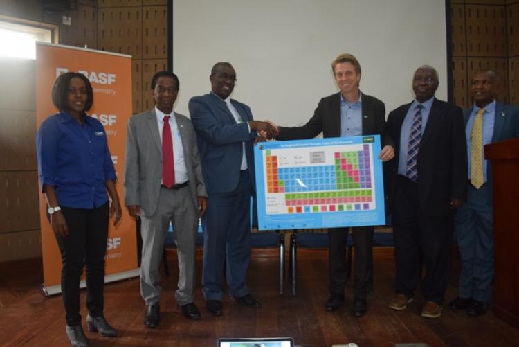 Principal, CBPS, representing the Vice Chancellor during BASF open day handing over both English & Kiswahili periodic table prepared by Department of Chemistry 